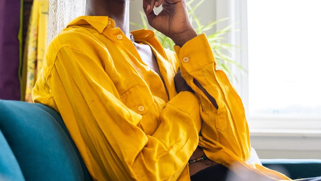 Black woman reading while relaxing on a sofa at home.